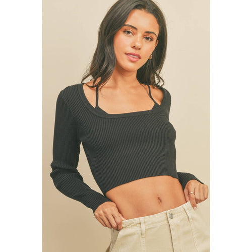 Woman wearing a black ribbed long-sleeve top and beige pants against a beige background