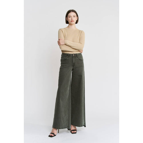 Woman wearing a beige top and dark green wide-leg jeans on a white background