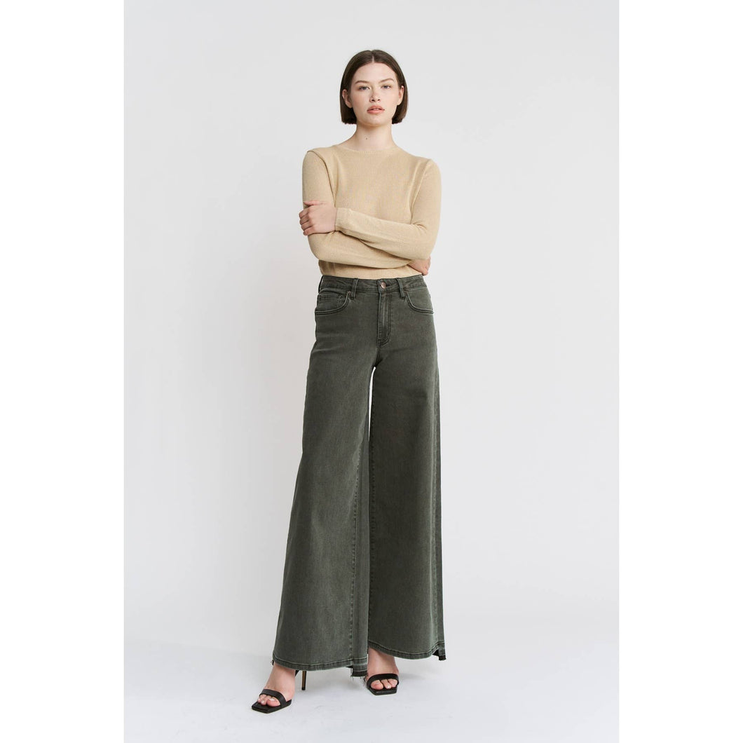 Woman wearing a beige top and dark green wide-leg jeans on a white background